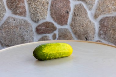 Bir salatalık masanın üzerinde oturuyor. Salatalık sarıdır ve üzerinde yeşil bir leke vardır.