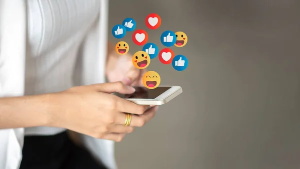Sosyal medya ve teknoloji kavramı. Sosyal ağlarda ikonla sohbet eden ve takip eden teknoloji eğilimlerine karşı akıllı telefon bağımlılığını kullanarak ellerinizi kapatın. bir çok ikon, beğeni, kalp ile çevrili