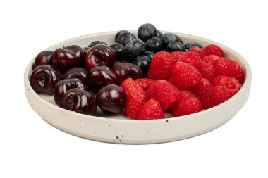 Vişne, ahududu ve böğürtlen de dahil olmak üzere karışık meyvelerin yüksek çözünürlüklü fotoğrafı bir tabakta bölünmüş odak tekniğiyle çekildi..