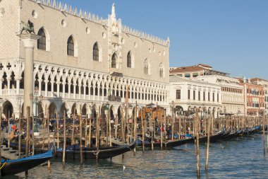 Doges palace and gondolas on water near embankment on Venice bay, Venice, Italy.