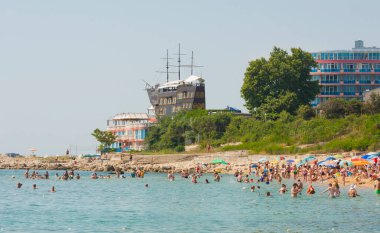 02 Temmuz 2015 - St. ConstANTINE VE HELENA RESORT, VARNA REJON, BULGARIA: Yelkenli gemi Sirius ve otel Sirius 'taki restoran ve yazın sahilde yüzen insanlar.