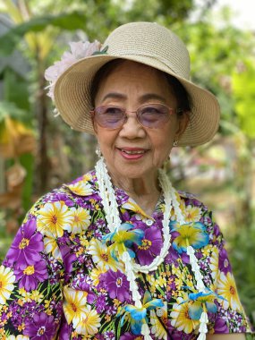 Bahçede şapka ve güneş gözlüğü takan Asyalı son sınıf öğrencisinin portresi..