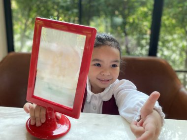 Beyaz elbiseli mutlu Asyalı kız öğrencinin portresi kafede boş bir ekran gösteriyor.