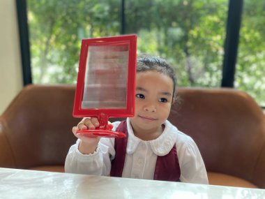 Beyaz elbiseli mutlu Asyalı kız öğrencinin portresi kafede boş bir ekran gösteriyor.