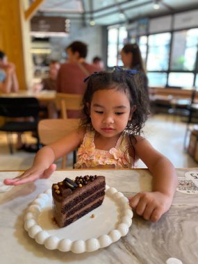 Küçük kız restoranda pasta yiyor.