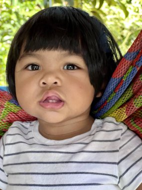 Hamakta oturup komik surat yapan Asyalı tatlı bir kızın portresi.