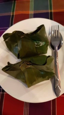 Yemek pişti ve muz yaprağına sarıldı. Masa örtüsünde çatal bıçak ve tabakla.