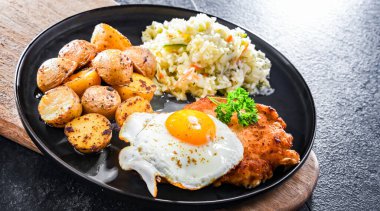 Kızarmış tavuk yumurtası, patates ve lahana ile servis edilen kızarmış tavuk pirzolası.