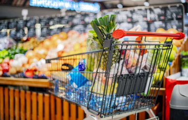 Süpermarkette market ürünleriyle dolu bir alışveriş arabası.