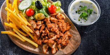Kebab served with french fries, vegetable salad and tzatziki