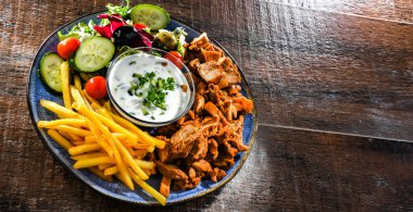 Kebab served with french fries, vegetable salad and tzatziki