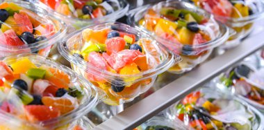Plastic boxes with pre-packaged fruit salads, put up for sale in a commercial refrigerator