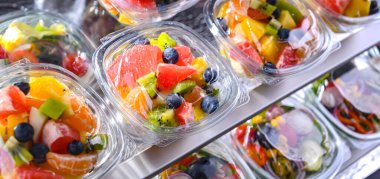 Plastic boxes with pre-packaged fruit salads, put up for sale in a commercial refrigerator