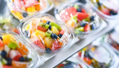 Plastic boxes with pre-packaged fruit salads, put up for sale in a commercial refrigerator