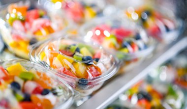 Plastic boxes with pre-packaged fruit salads, put up for sale in a commercial refrigerator