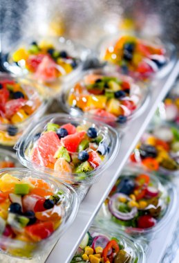 Plastic boxes with pre-packaged fruit salads, put up for sale in a commercial refrigerator