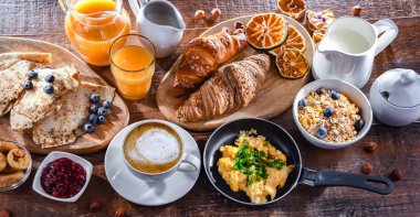 Breakfast served with coffee, orange juice, scrambled eggs, cereals, pancakes and croissants.