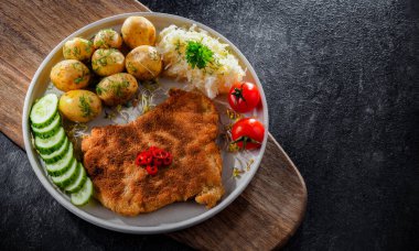 Patates ve lahana ile servis edilen ekmek kırıntılarıyla kaplı domuz pirzolası.