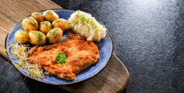 Patates ve lahana ile servis edilen ekmek kırıntılarıyla kaplı domuz pirzolası.