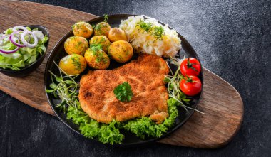 Patates ve lahana ile servis edilen ekmek kırıntılarıyla kaplı domuz pirzolası.