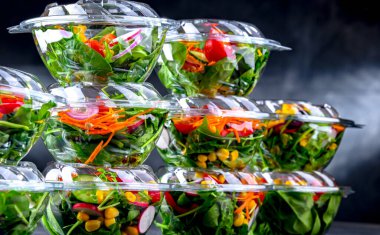 Önceden paketlenmiş sebze salatalarıyla dolu plastik kutular. Ticari bir buzdolabında satılıyor.