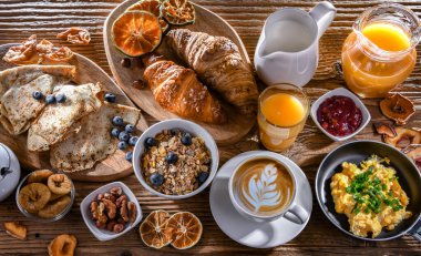 Breakfast served with coffee, orange juice, scrambled eggs, cereals, pancakes and croissants.
