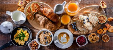 Breakfast served with coffee, orange juice, scrambled eggs, cereals, pancakes and croissants.