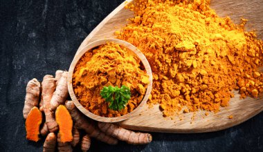 Bir kase zemin zerdeçal ve taze rhizomu ile kompozisyon.