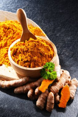 Bir kase zemin zerdeçal ve taze rhizomu ile kompozisyon.