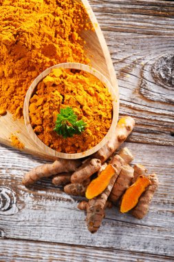 Bir kase zemin zerdeçal ve taze rhizomu ile kompozisyon.