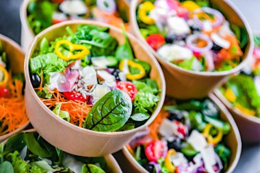 Yuvarlak karton kutular ve önceden paketlenmiş sebze salataları satışa hazır.