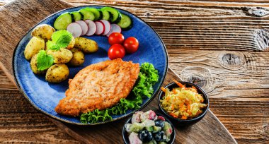 Patates ve sebze salatalı ekmek kırıntılarıyla kaplı domuz pirzolası.