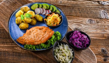 Patates ve sebze salatalı ekmek kırıntılarıyla kaplı domuz pirzolası.