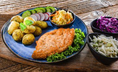 Patates ve sebze salatalı ekmek kırıntılarıyla kaplı domuz pirzolası.