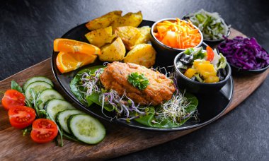 Patates ve sebze salatalı ekmek kırıntılarıyla kaplanmış tavuk pirzolası.