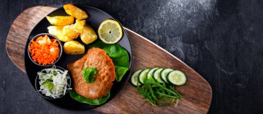 Patates ve sebze salatalı ekmek kırıntılarıyla kaplı domuz pirzolası.