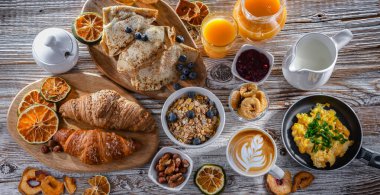 Breakfast served with coffee, orange juice, scrambled eggs, cereals, pancakes and croissants.