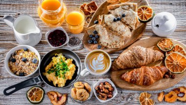 Breakfast served with coffee, orange juice, scrambled eggs, cereals, pancakes and croissants.