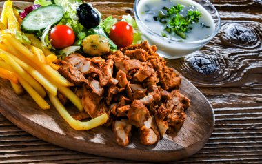 Kebab served with french fries, vegetable salad and tzatziki