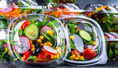 Önceden paketlenmiş sebze salatalarıyla dolu plastik kutular. Ticari bir buzdolabında satılıyor.