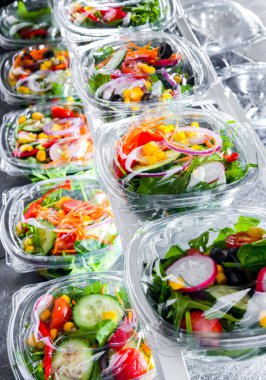 Önceden paketlenmiş sebze salatalarıyla dolu plastik kutular. Ticari bir buzdolabında satılıyor.