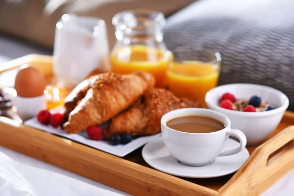 A tray with breakfast on a bed in a hotel room.