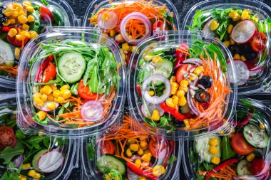 Önceden paketlenmiş sebze salatalarıyla dolu plastik kutular. Ticari bir buzdolabında satılıyor.