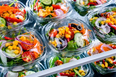 Önceden paketlenmiş sebze salatalarıyla dolu plastik kutular. Ticari bir buzdolabında satılıyor.