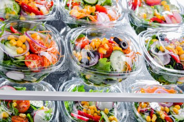 Önceden paketlenmiş sebze salatalarıyla dolu plastik kutular. Ticari bir buzdolabında satılıyor.