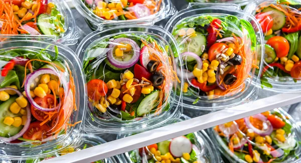 stock image Plastic boxes with pre-packaged vegetable salads, put up for sale in a commercial refrigerator