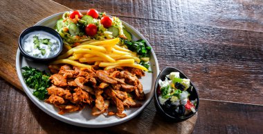 Kebab served with french fries, vegetable salad and tzatziki