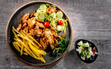 Kebab served with french fries, vegetable salad and tzatziki