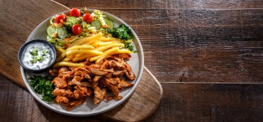Kebab served with french fries, vegetable salad and tzatziki