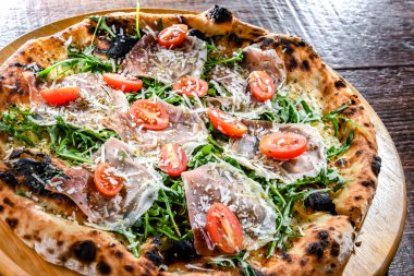 Pizza Italiana jambon, peynir, domates ve roka ile servis edilir..